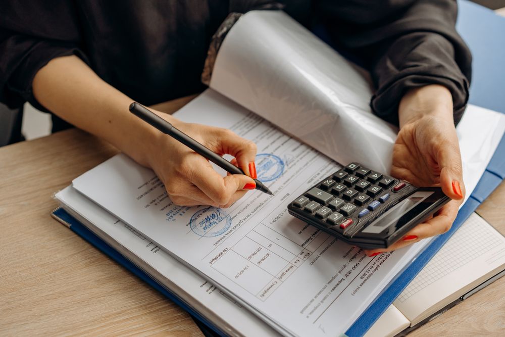 Persona revisando documentos financieros con calculadora